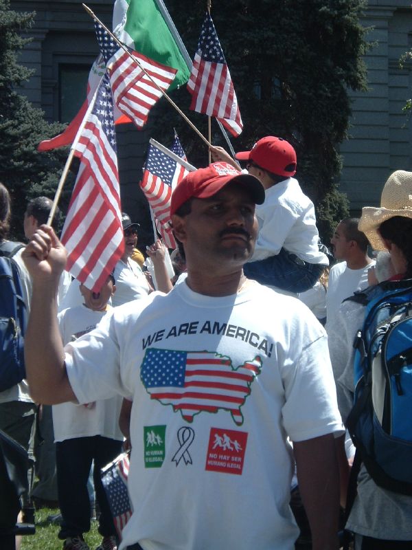 a man holding up several flags that say we are america