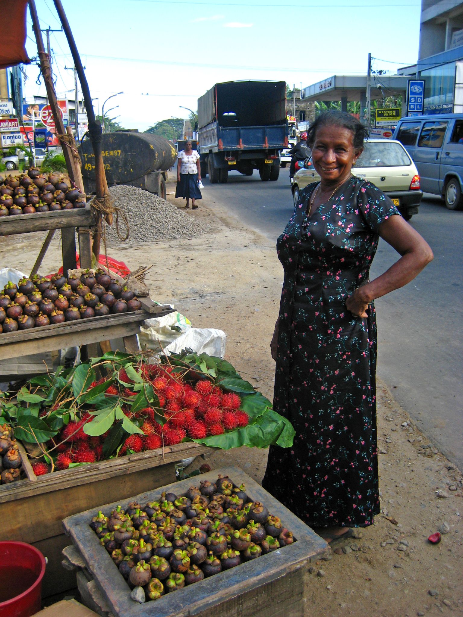 a woman smiling in front of produce stand