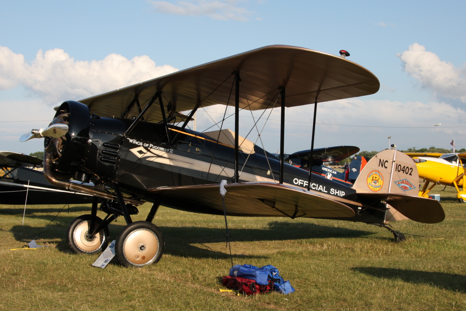 an old style plane parked in the grass