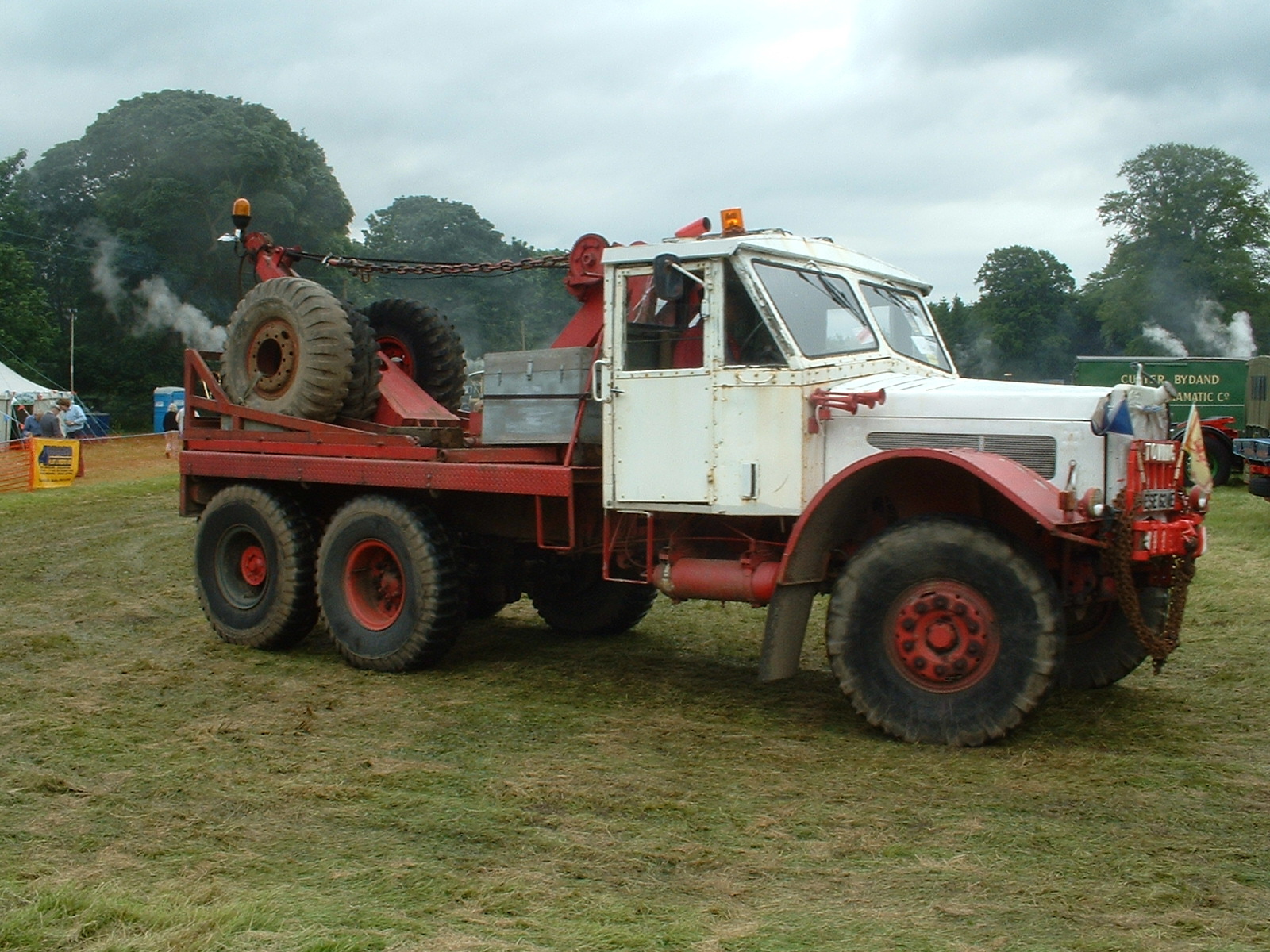 there is a white tow truck with large tires on a grassy area