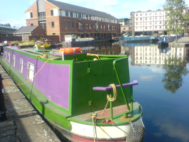 a green and purple boat docked in front of some buildings