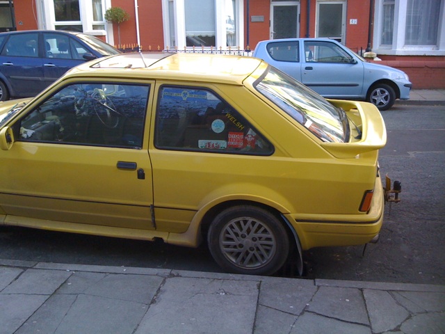 a small yellow car is parked along a side walk