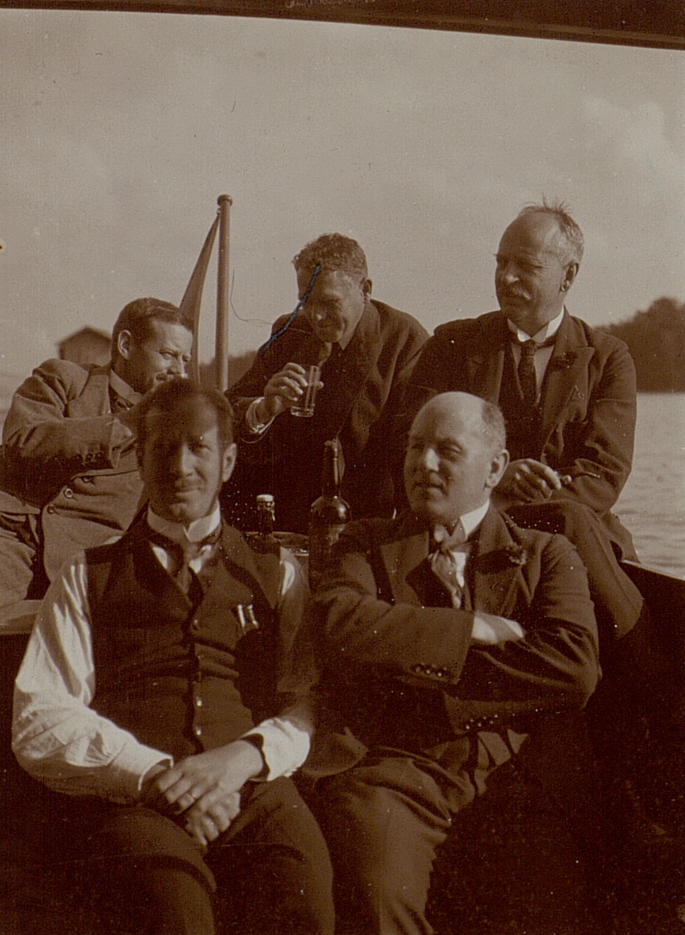 black and white pograph of five men on deck, four smiling