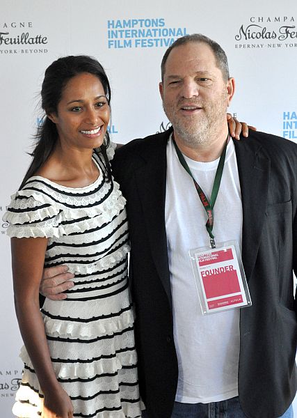 a man in a striped suit poses with a woman on a carpet
