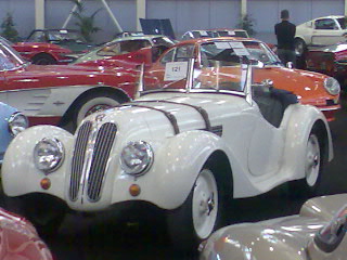 an old car and some other cars in a showroom