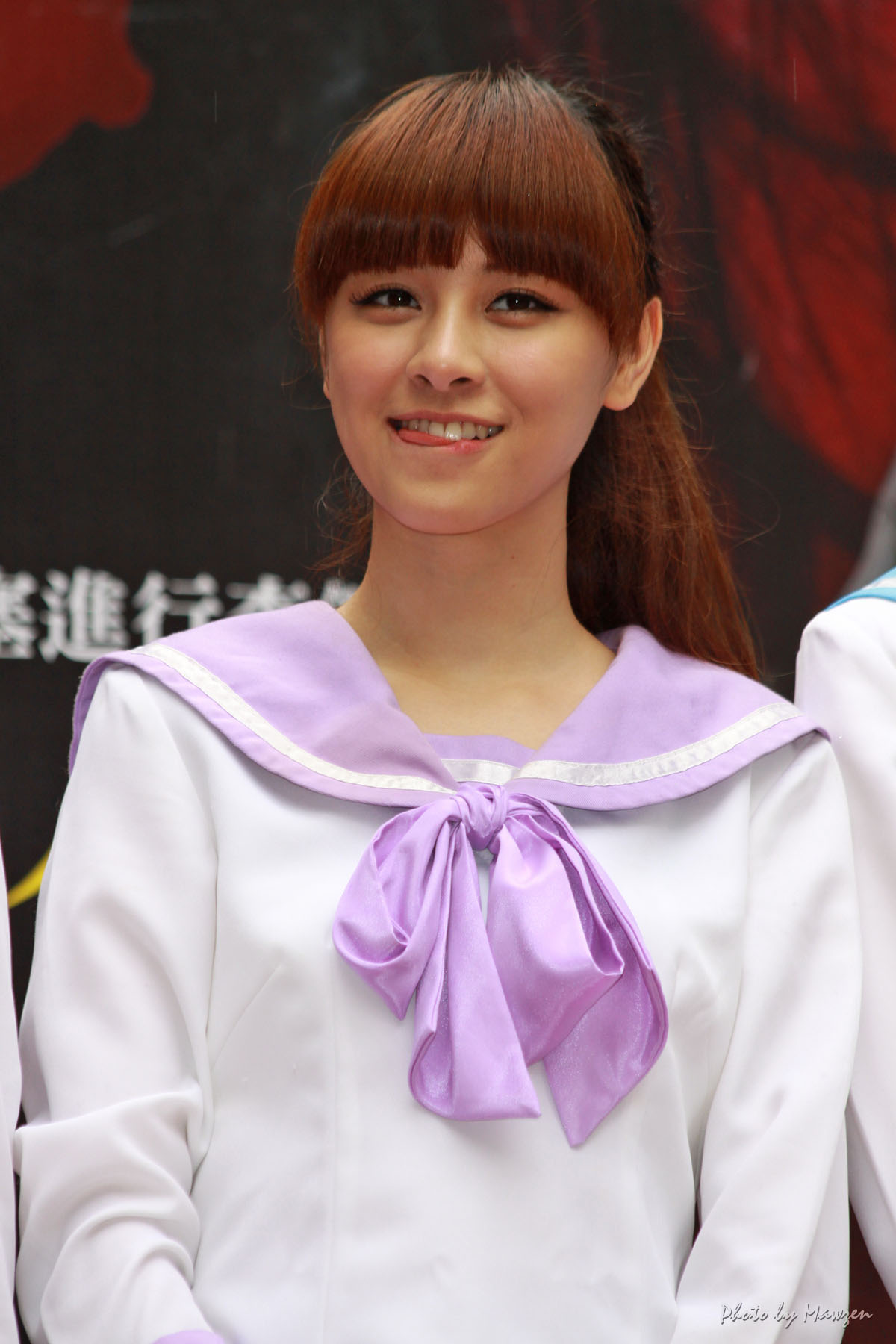 a young woman with long hair and a purple ribbon in front of a wall