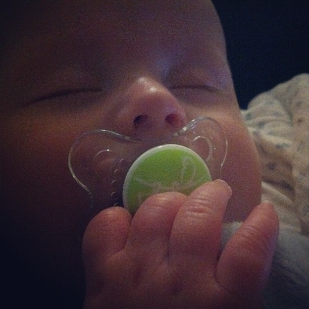 a baby holding a pacifier in its mouth