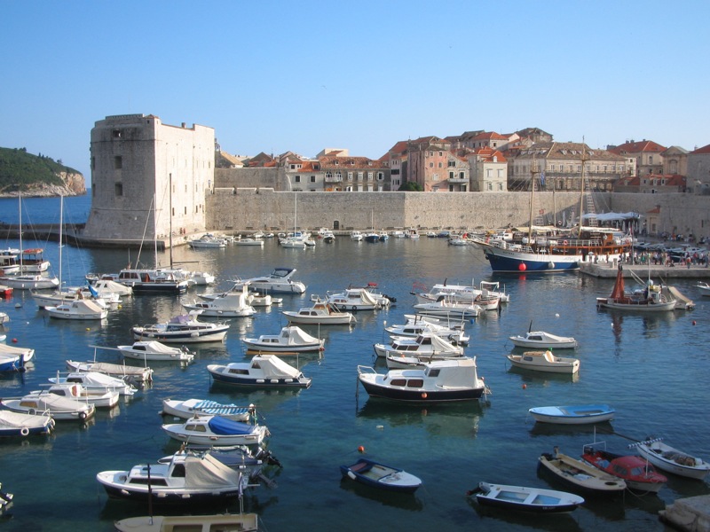 boats docked in the harbor by a very old castle