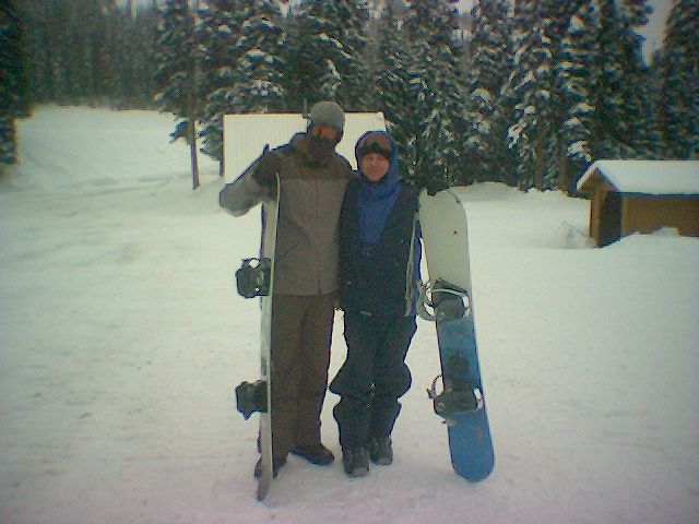 a man and woman holding a snowboard on the snow