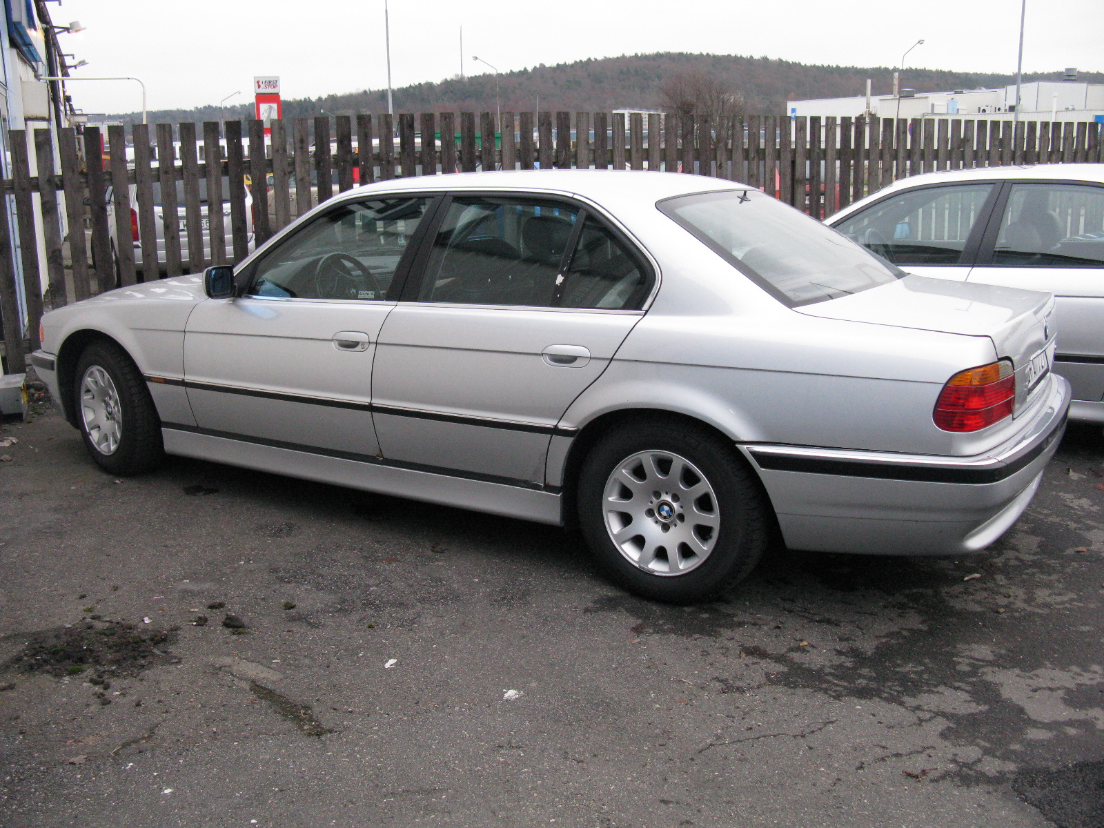 silver bmw car is parked next to the fence