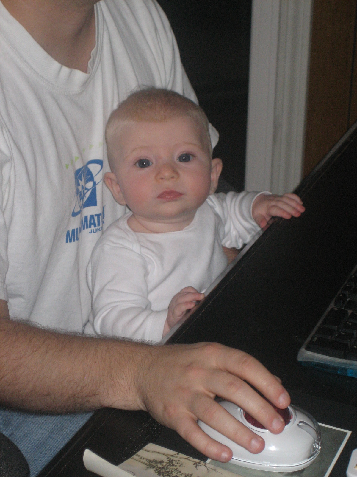 a man holding a baby while sitting in front of a laptop