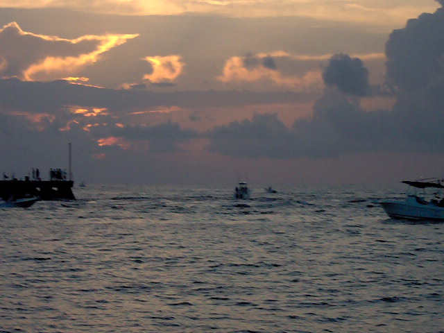 several boats are anchored in the water at sunset