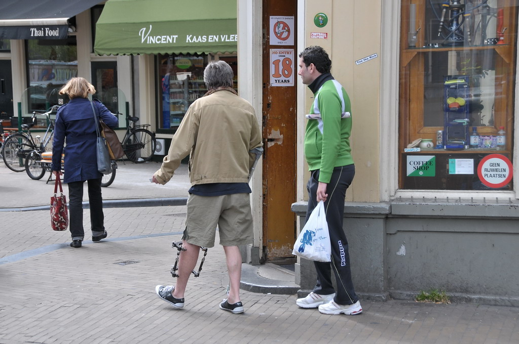 three people standing on a sidewalk with a shopping bag