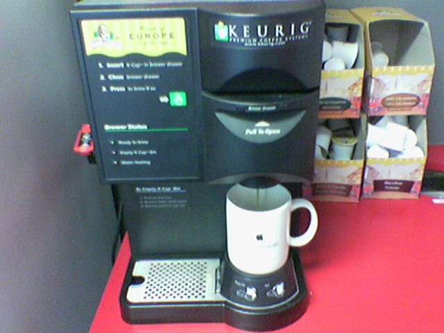there is a small coffee machine with a coffee cup on the counter