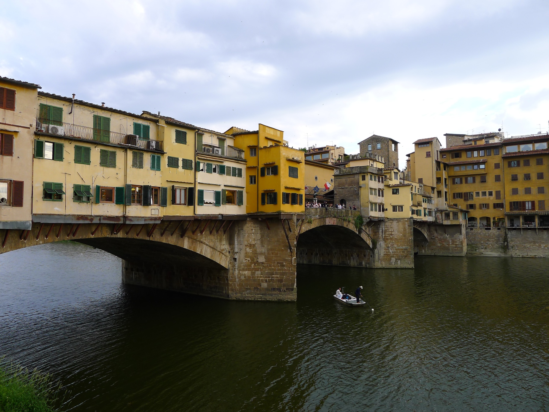 a cityscape shows two bridges, one connected to another and people in a boat