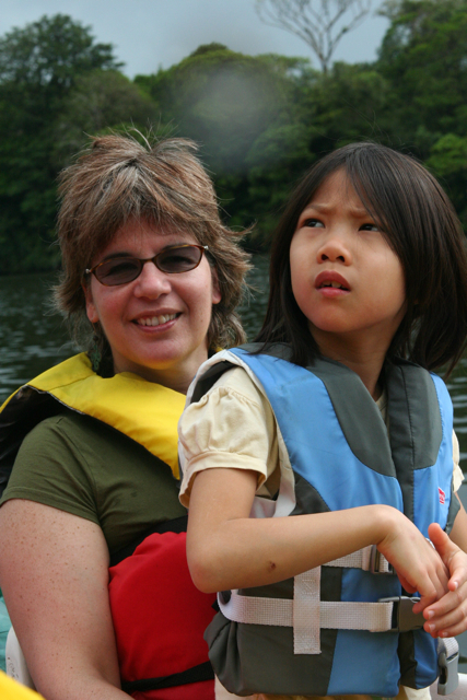 a girl sitting on the back of a woman on a boat