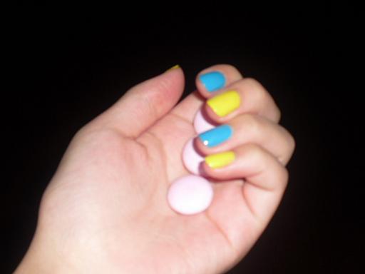 a hand that has a bunch of pink and yellow fingernails on it