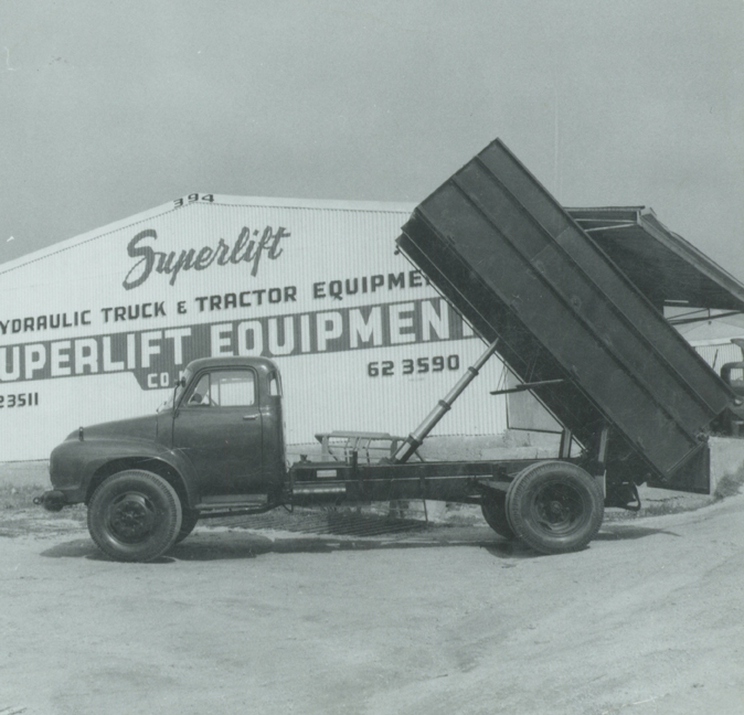 a large black dump truck in front of a shop sign