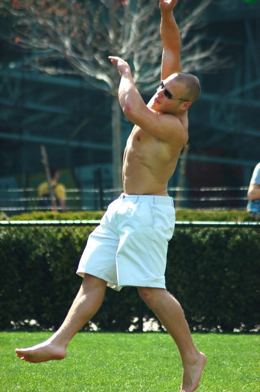 a man with  on reaching high in the air to catch a frisbee