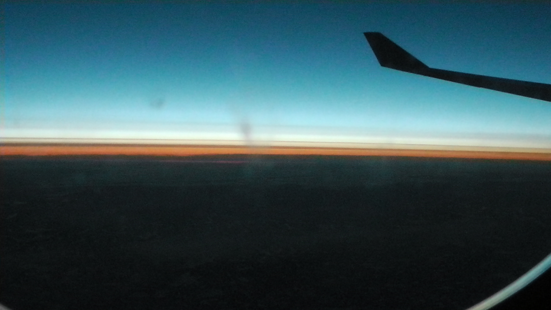 a plane wing with an airplane window and the sun coming down