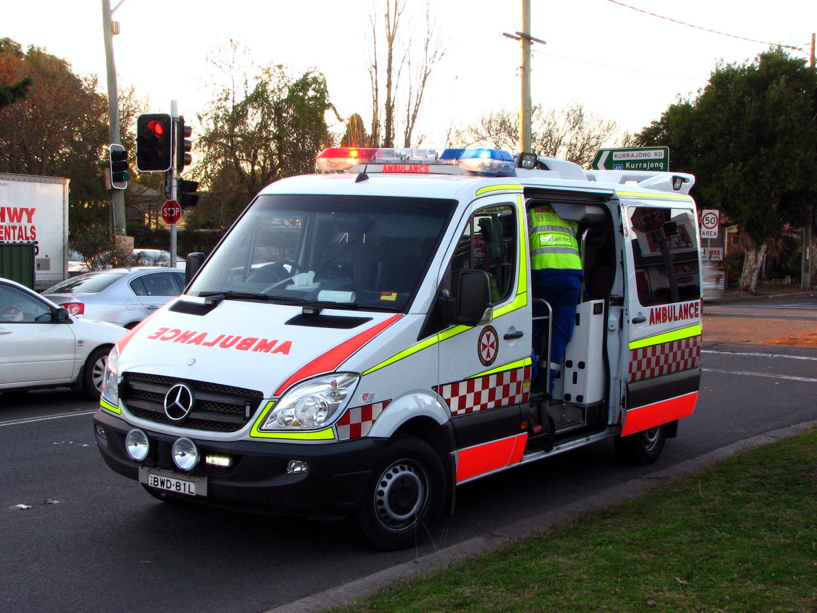 an ambulance is driving through the road with people on top