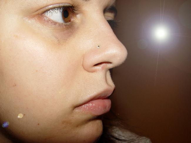 a close up of the face of a woman with a flashlight in her ear