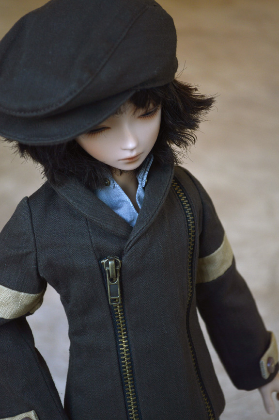 a doll dressed in a black and gold jacket