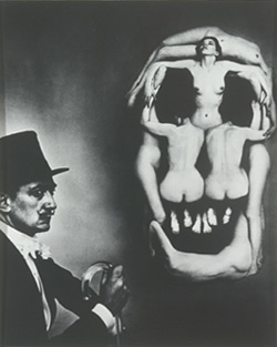 man leaning next to an enormous skull