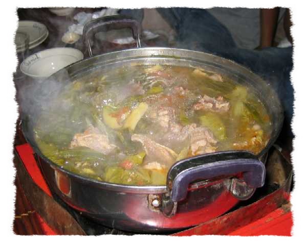 soup with meat and vegetables is being prepared on the stove top