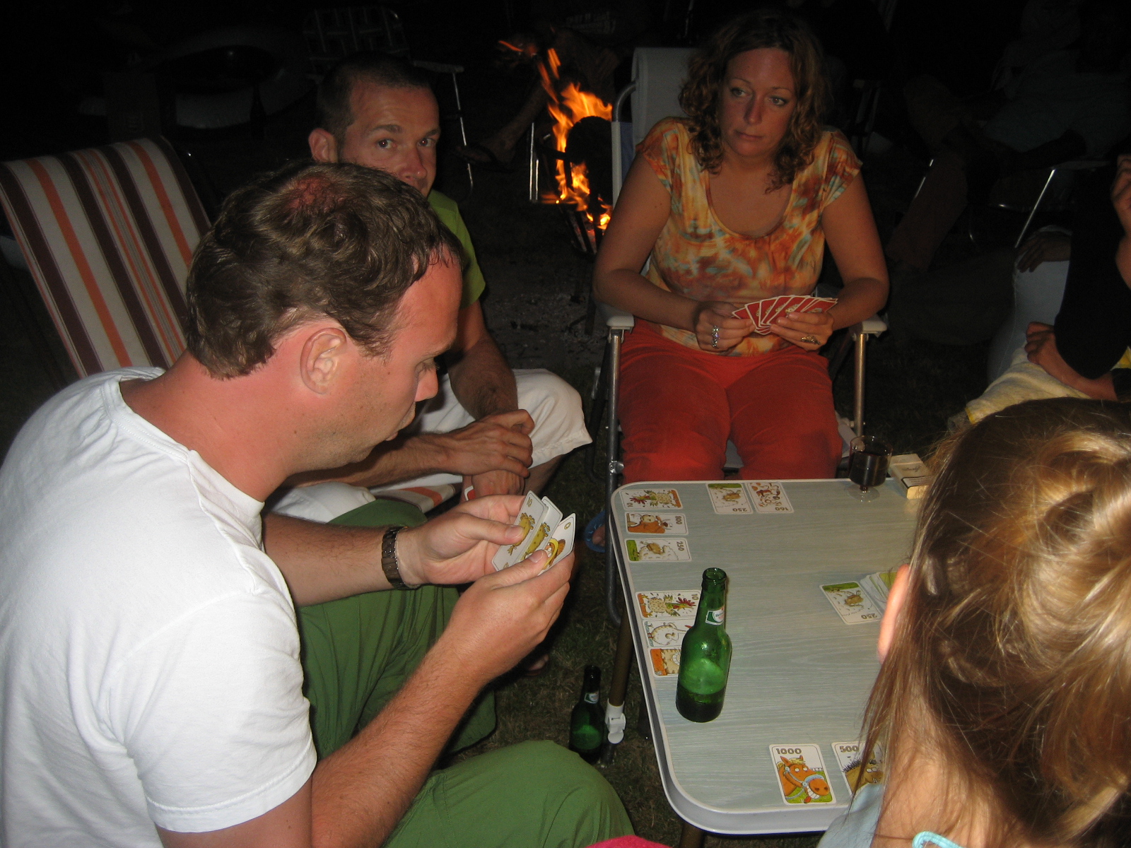 four people are sitting around playing cards