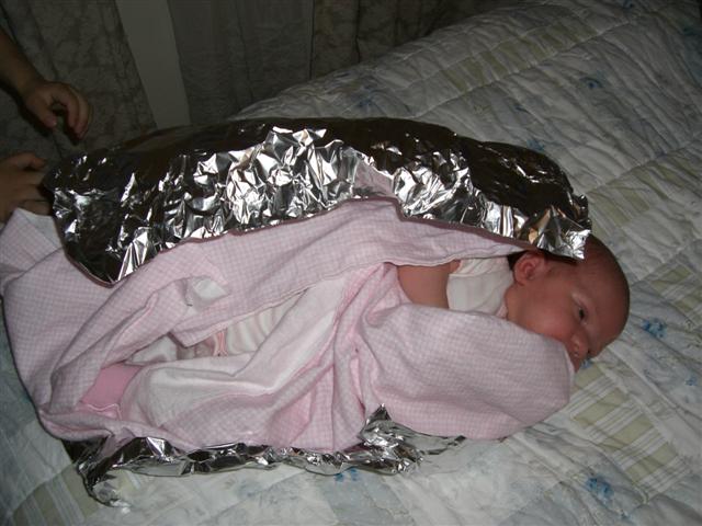 a baby wrapped in tinfoil is laying on a bed