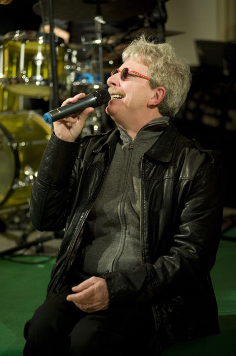 a man is sitting and singing into a microphone
