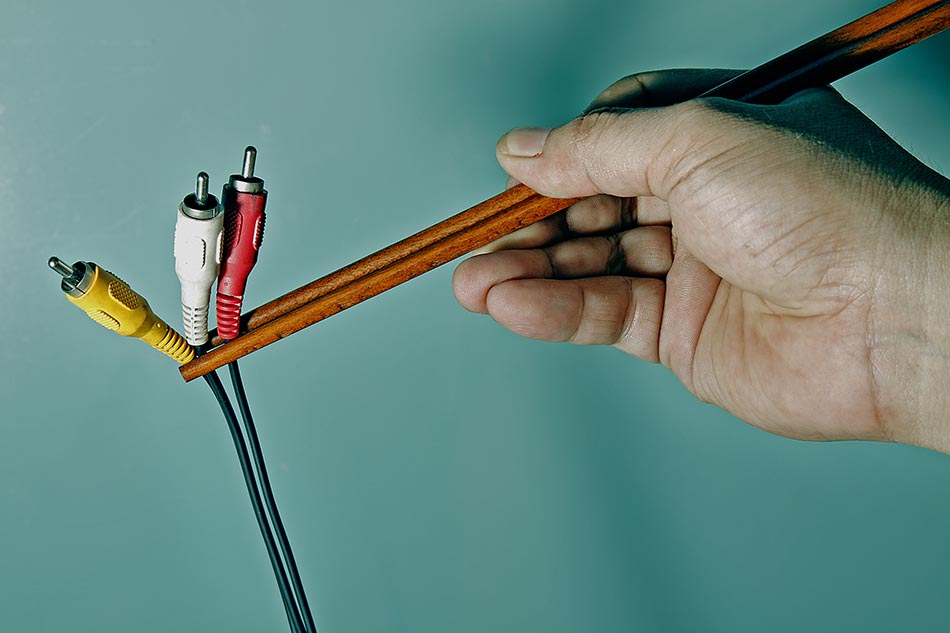 a hand holding a small pencil over a pair of electrical cords