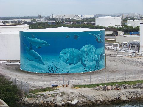 two dolphins in the water beside some tanks
