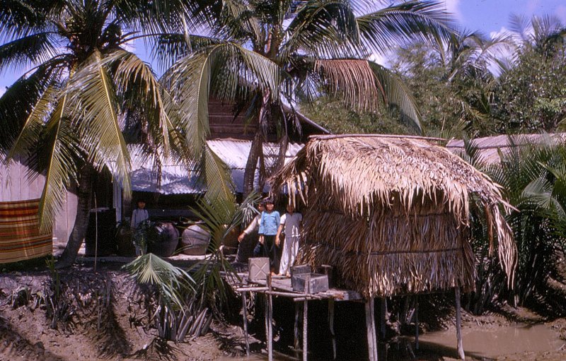 a man standing in front of some shack next to a tree