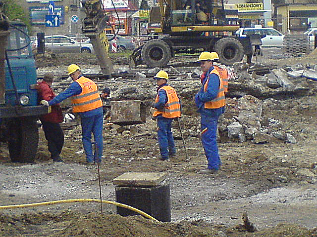 construction workers stand in the dirt on the street