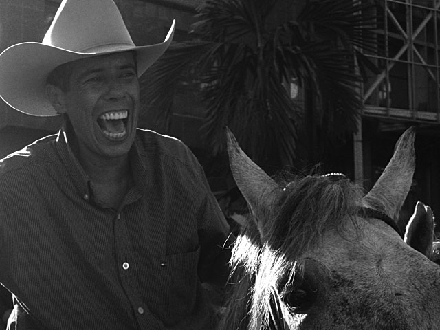 a man laughing while standing beside a horse