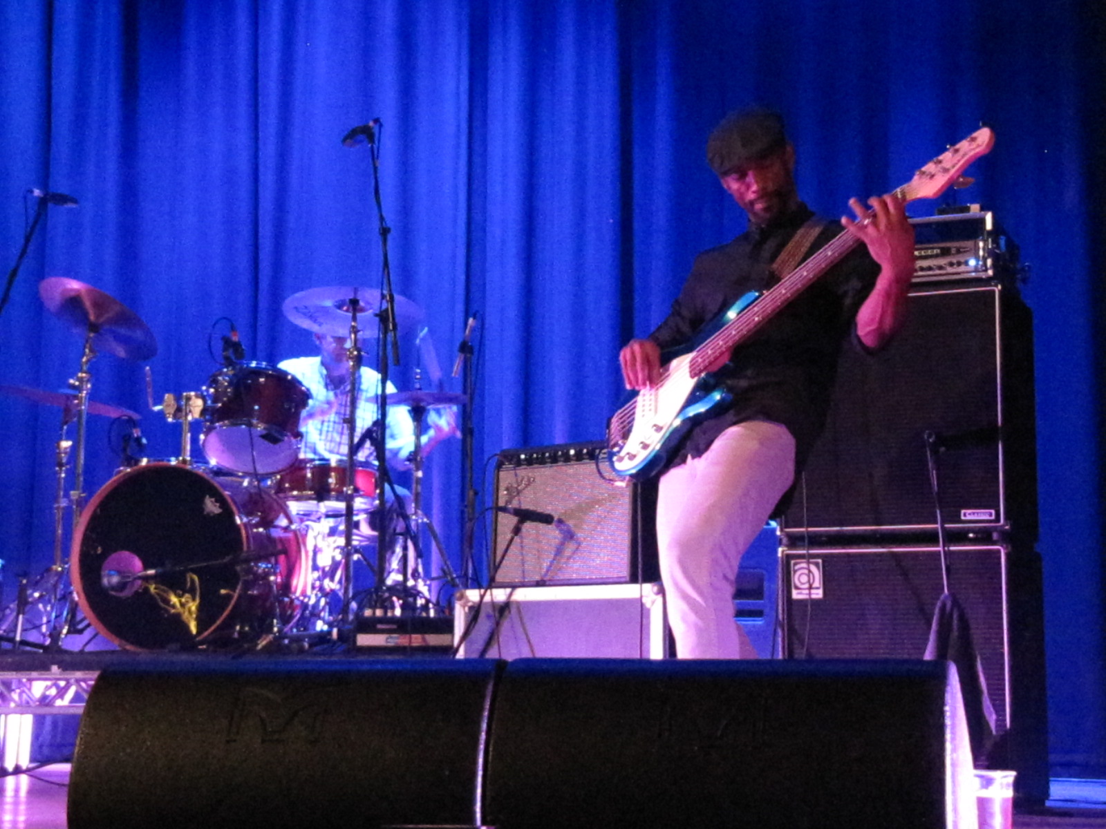 a person playing guitar on stage with blue curtains