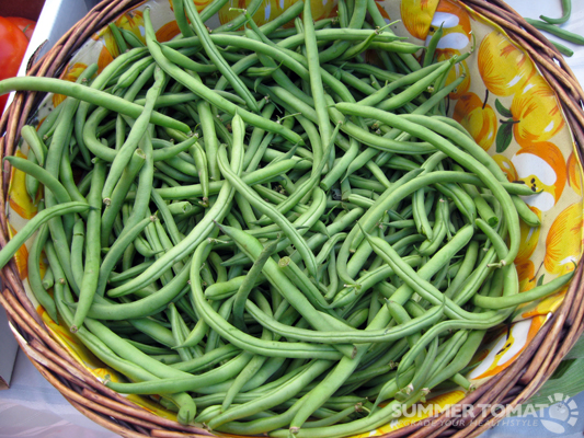 a wicker bowl full of green beans and fruit
