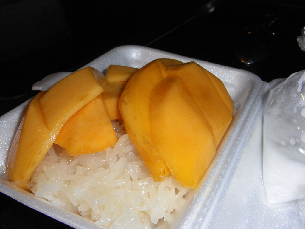 a plastic container with rice and mango slices