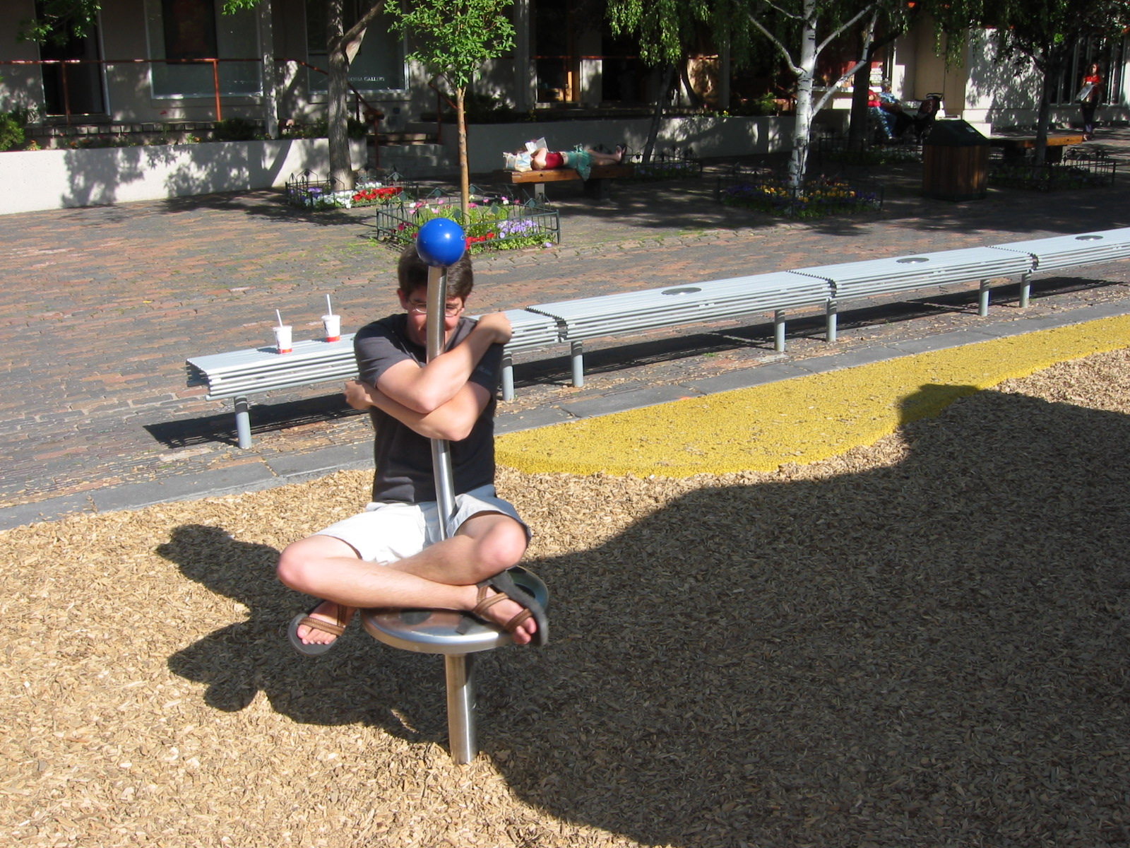 a man sitting on a metal bench on top of gravel