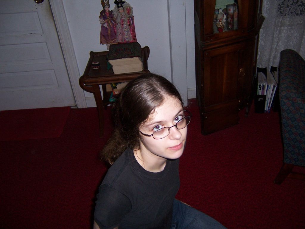 a little girl sitting on the ground with some glasses on