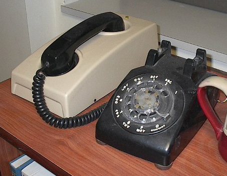 an old style telephone sitting on a desk next to another phone