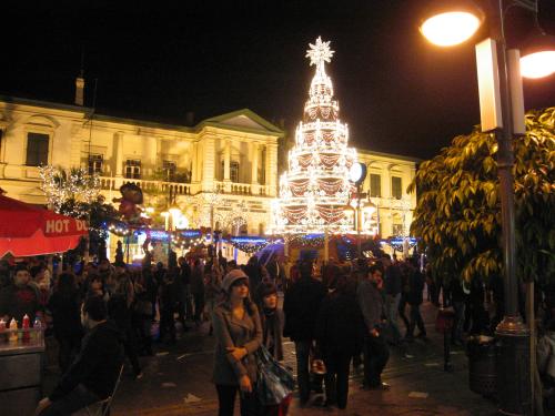 a large group of people walking around a christmas tree