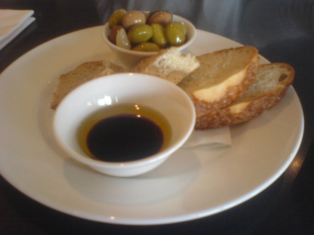 olives and bread are served on a white plate