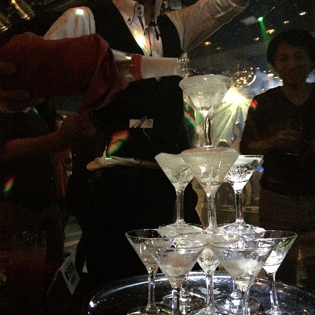 a woman pouring some drinks into glasses on a table