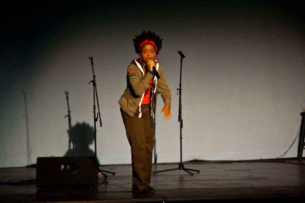 a woman standing on stage with microphones in the background