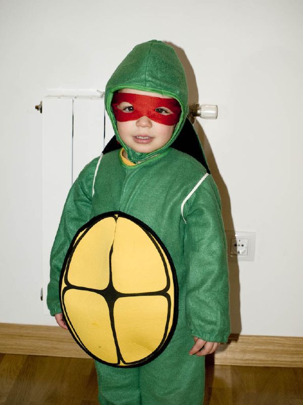a  dressed as a turtle is holding a pizza