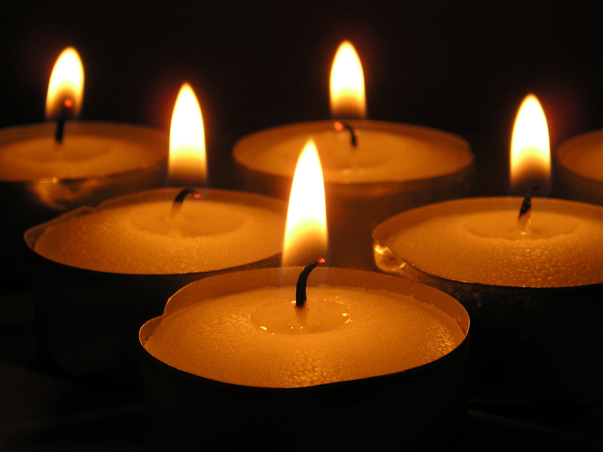 many candles lit and surrounded by black background