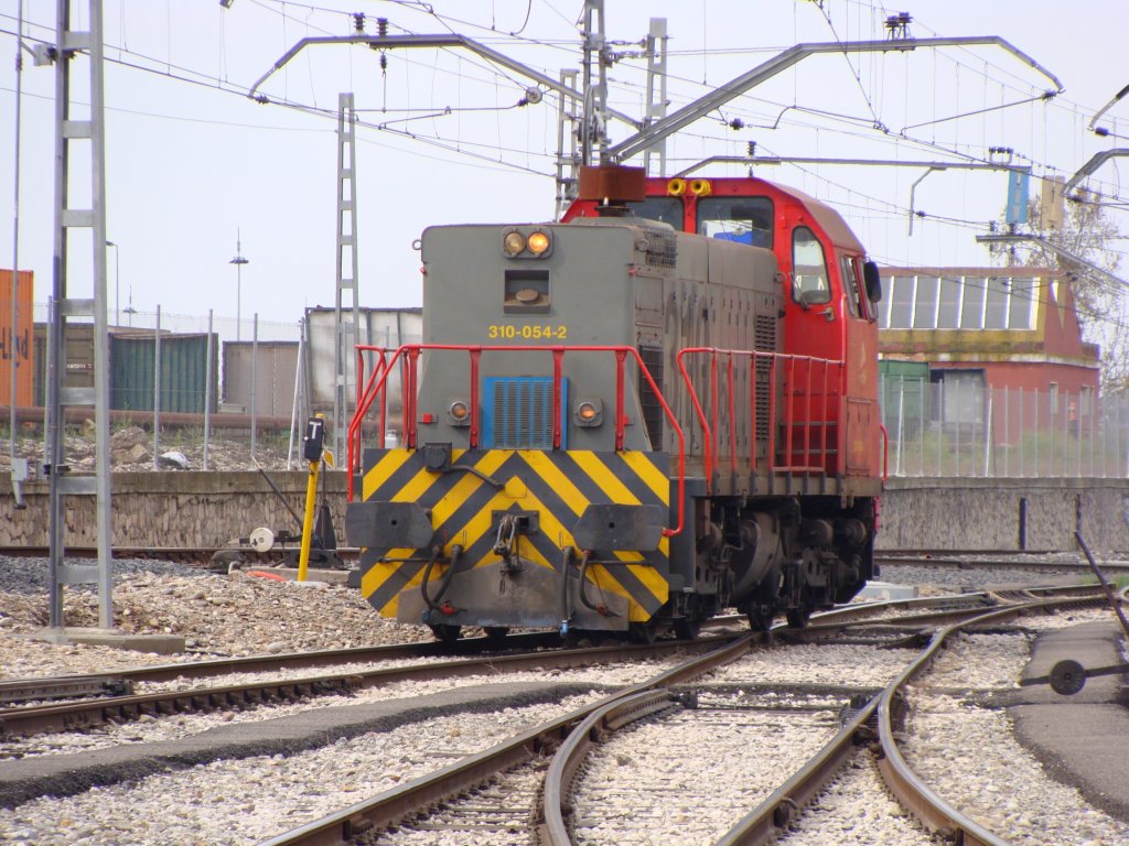 a red and grey train passing by two yellow and gray lines